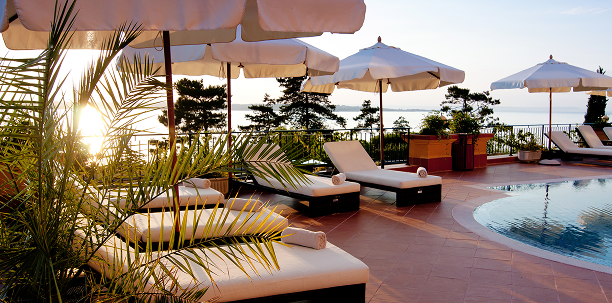 A resort pool area with lounge chairs and umbrellas at sunset.